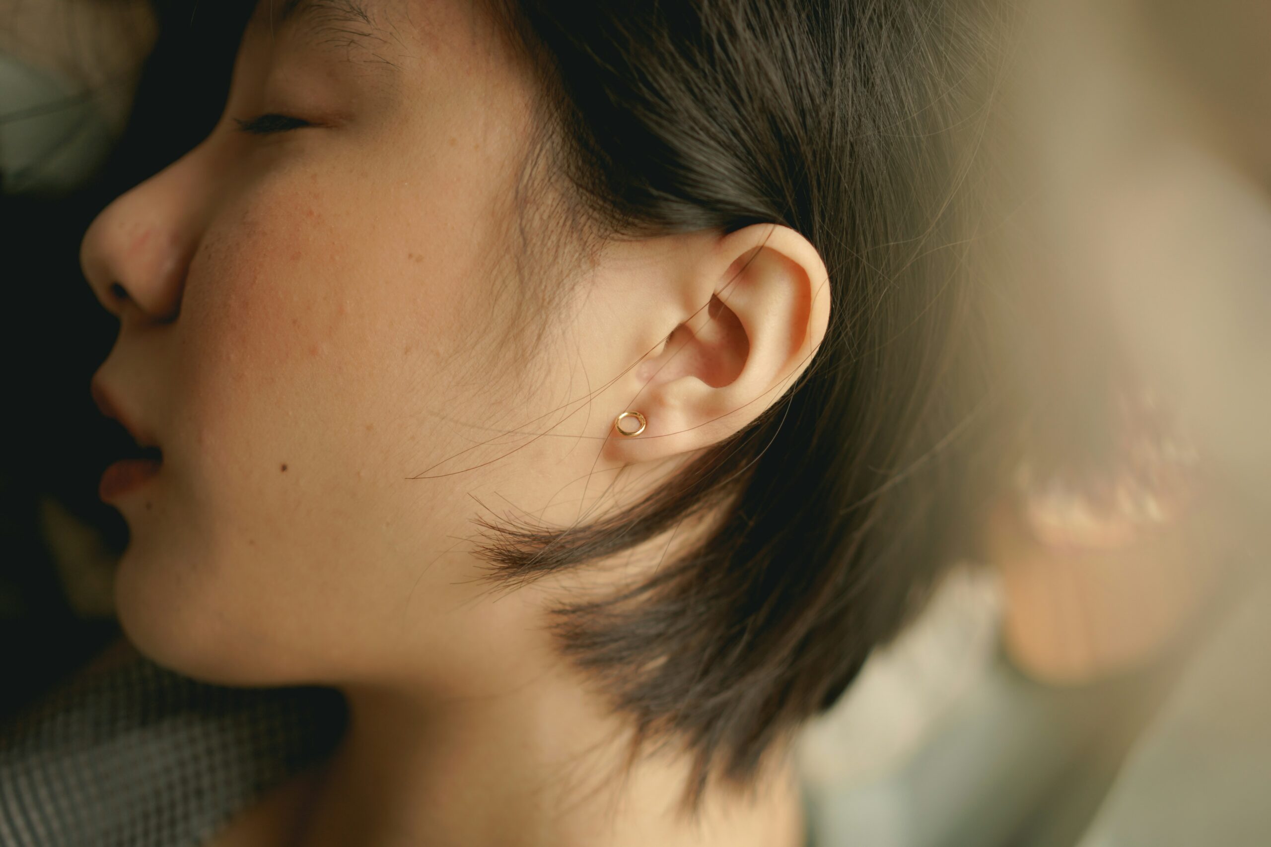 Photographie de l'oreille d'une femme allongée sur le coté. Son oreille est prise en photo en gros plan.